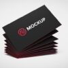 Stack of premium laminated business cards with a black matte finish and red edges, showcasing a mockup logo. Ideal for professional branding.