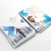 Two stacks of A6 flyers with a modern blue geometric design, showcasing business themes, a man smiling, and a person walking in a city.